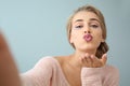 Beautiful young woman blowing kiss while taking selfie on color background Royalty Free Stock Photo
