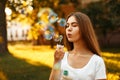 Beautiful young woman blowing soap bubbles in the park Royalty Free Stock Photo