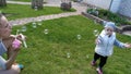 Beautiful young woman blows soap bubbles for her little son. Happy boy runs after the soap bubbles Royalty Free Stock Photo