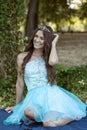 Beautiful young woman in a blue dress posing with a crown on her