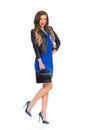 Beautiful Young Woman In Blue Mini Dress And Leather Jacket Is Standing On One Leg With Black Bag Royalty Free Stock Photo