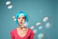 Beautiful young woman with blue wig and bright make-up in soap bubbles. Fashion model girl with creative color makeup Royalty Free Stock Photo