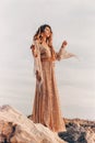 Beautiful young woman in boho dress on the beach at sunset