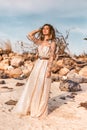 Beautiful young woman in boho dress on the beach at sunset