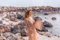 Beautiful young woman in boho dress and wreath on the beach at sunset