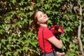 Beautiful young woman with a bouquet of flowers near a green wall of bushes. Floral business. Copy space Royalty Free Stock Photo