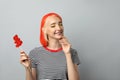 Beautiful young woman with bright dyed hair holding bear shaped candy on light grey background Royalty Free Stock Photo