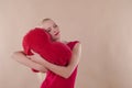 Beautiful young woman in a bright red slinky dress hugging a plush heart Royalty Free Stock Photo