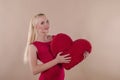 Beautiful young woman in a bright red slinky dress hugging a plush heart Royalty Free Stock Photo