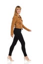 Young Woman In Brown Suede Jacket Is Walking And Looking At Camera. Side View Royalty Free Stock Photo