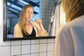 Beautiful young woman brushing her teeth with tooth brush in front of bathroom mirror Royalty Free Stock Photo