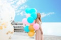 Beautiful young woman with bunch of balloons near sightseeing boat