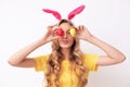 Beautiful young woman in bunny ears headband holding Easter eggs near eyes Royalty Free Stock Photo