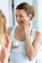 Beautiful young woman caring of her skin standing near mirror in the bathroom. Royalty Free Stock Photo