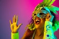 Beautiful young woman in carnival and masquerade costume on gradient studio background in neon light Royalty Free Stock Photo