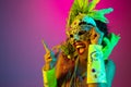 Beautiful young woman in carnival and masquerade costume on gradient studio background in neon light Royalty Free Stock Photo