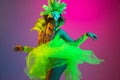 Beautiful young woman in carnival and masquerade costume on gradient studio background in neon light Royalty Free Stock Photo