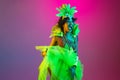 Beautiful young woman in carnival and masquerade costume on gradient studio background in neon light Royalty Free Stock Photo