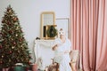 Beautiful young woman in a carnival rabbit mask and white costume celebrates the new year near the Christmas tree in a modern Royalty Free Stock Photo