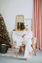 Beautiful young woman in a carnival rabbit mask and white costume celebrates the new year near the Christmas tree in a modern Royalty Free Stock Photo