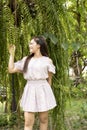 Beautiful young woman in casual clothes walks through green forest in summer and admires wild flowers, concept Leisure of young