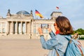 Young woman in casual wear taking photos by her mobile phone at the Bundestag, Berlin