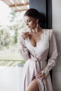 Beautiful young woman in a chic pink bathrobe spends time alone in an expensive hotel in the summer during the holidays Royalty Free Stock Photo