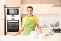 Beautiful young woman with clean dishes and cups at table Royalty Free Stock Photo