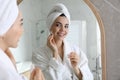 Beautiful young woman cleaning her face with cotton disk near mirror in bathroom Royalty Free Stock Photo