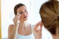 Beautiful young woman is cleaning her face while looking in the bathroom. Royalty Free Stock Photo