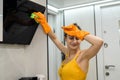 Beautiful and young woman cleaning kitchen hood from dust Royalty Free Stock Photo