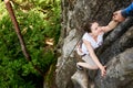 Beautiful young woman climbing on rock outdoors in summer. Top view. Happy girl climbing rock trekking outdoors