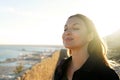 Beautiful young woman with closed eyes breathing with wind on her face relaxing enjoying sun at sunset. Beauty sunshine girl side Royalty Free Stock Photo