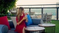 Beautiful young woman with cocktail drink at luxury rooftop restaurant enjoy cityscape during sunset. Elegant female in Royalty Free Stock Photo