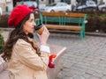 Beautiful young woman with coffee to go and spring tulips flowers bouquet at city street. Happy girl walking outdoors. Spring Royalty Free Stock Photo