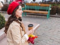 Beautiful young woman with coffee to go and spring tulips flowers bouquet at city street. Happy girl walking outdoors. Spring Royalty Free Stock Photo