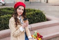 Beautiful young woman with coffee to go and spring tulips flowers bouquet at city street. Happy girl walking outdoors. Spring Royalty Free Stock Photo