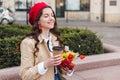 Beautiful young woman with coffee to go and spring tulips flowers bouquet at city street. Happy girl walking outdoors. Spring Royalty Free Stock Photo