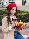 Beautiful young woman with coffee to go and spring tulips flowers bouquet at city street. Happy girl walking outdoors. Spring Royalty Free Stock Photo