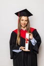 Beautiful young woman college graduate portrait wearing cap and gown with diploma isolated on white background Royalty Free Stock Photo