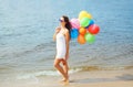 Beautiful young woman with colorful balloons over sea Royalty Free Stock Photo