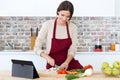 Beautiful young woman cooking and using digital tablet in the kitchen. Royalty Free Stock Photo
