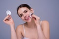Beautiful young woman with cotton pad, applying lotion on face, removing makeup. Skin care. Studio portrait of girl Royalty Free Stock Photo