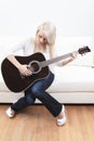 Beautiful young woman on the couch with a guitar
