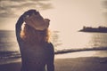 Beautiful young woman with cowboy hat and golden hair look an amazing coloured sunset over the ocean in vacation leisure anjoyed Royalty Free Stock Photo