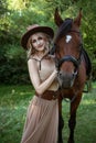 Beautiful young woman in a cowboy hat near a horse on nature Royalty Free Stock Photo