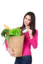 Beautiful young woman with credit card holding paper bag with groceries. Isolated. Shopping and groceries concept. Royalty Free Stock Photo