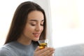 Beautiful young woman with cup of hot tea near window at home Royalty Free Stock Photo