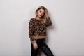 Beautiful young woman with curly blond hair in a stylish leopard sweater in trendy black leather pants posing in a studio Royalty Free Stock Photo