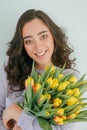 Beautiful young woman with curly hair holds a bouquet of tulips. Women`s Day. Spring Royalty Free Stock Photo